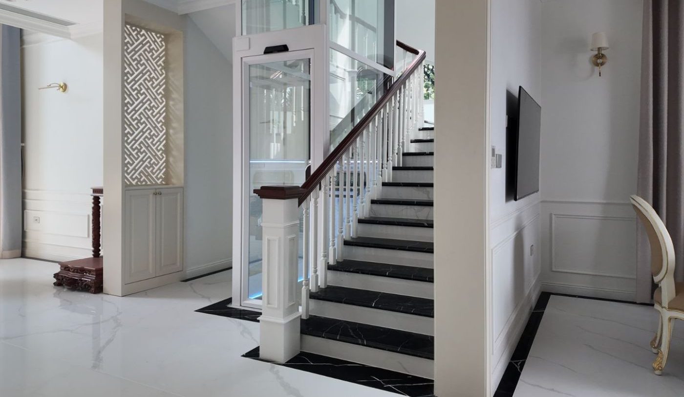 Thang máy trục vít khung trắng cạnh thang bộ